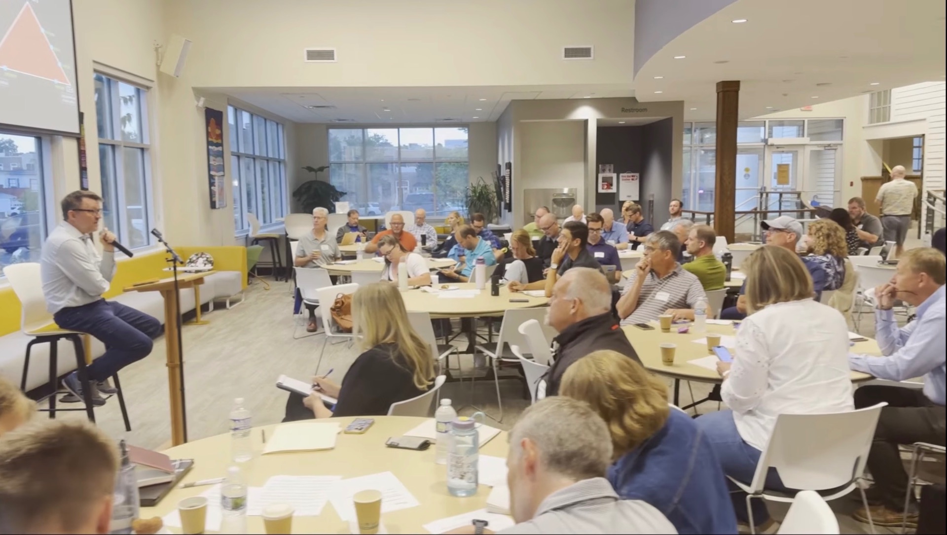Andrew Root speaking to pastors and church leaders seated at round tables during the Church Now Cafe